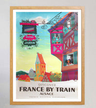 Load image into Gallery viewer, Framed travel poster for France by train featuring colorful buildings and 'Hotel Jardin' sign.