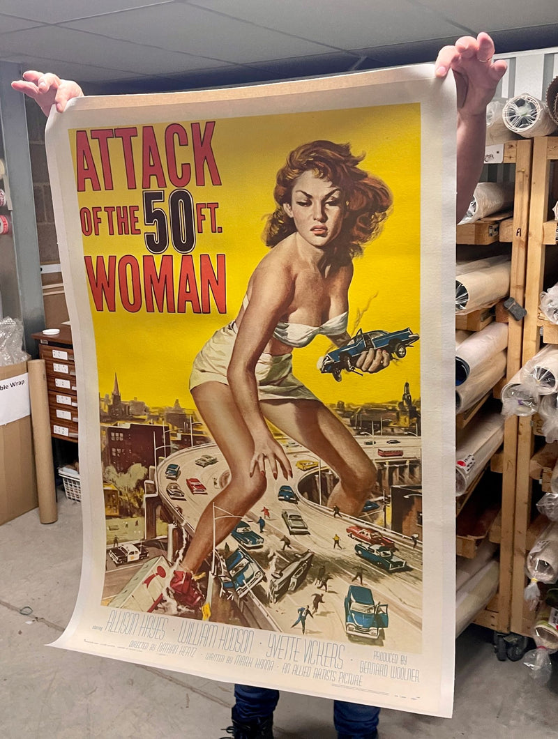 A linen-backed original one-sheet poster for Attack of the 50 Ft. Woman, held up to show its full size and condition