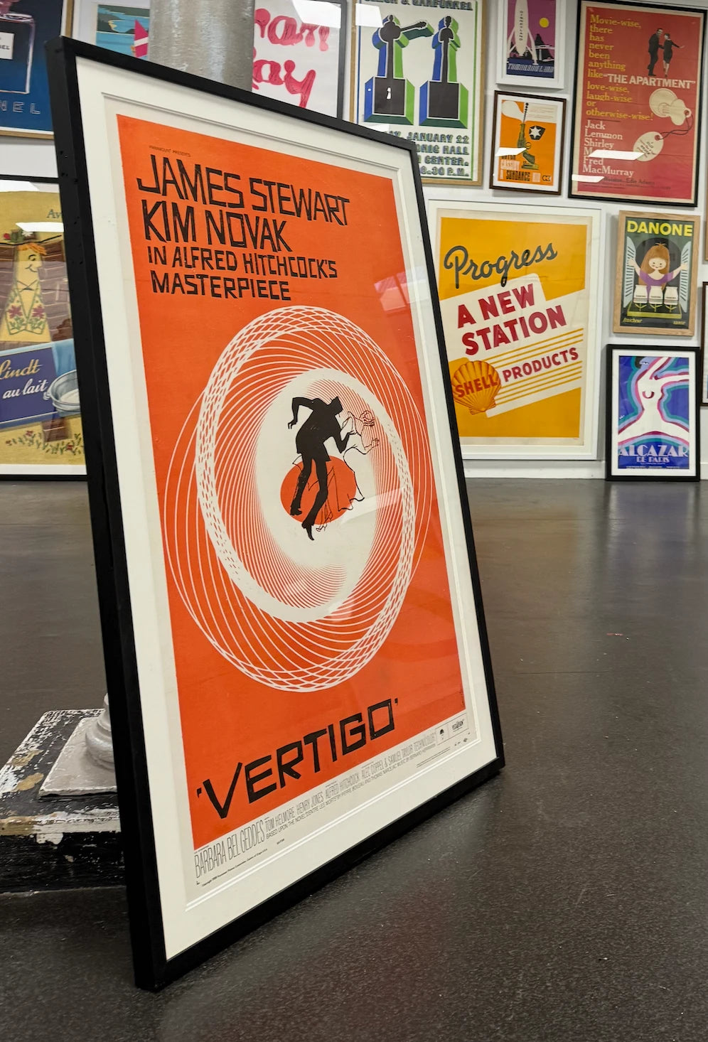 A framed Vertigo poster leaning in front of a wall of other original vintage posters
