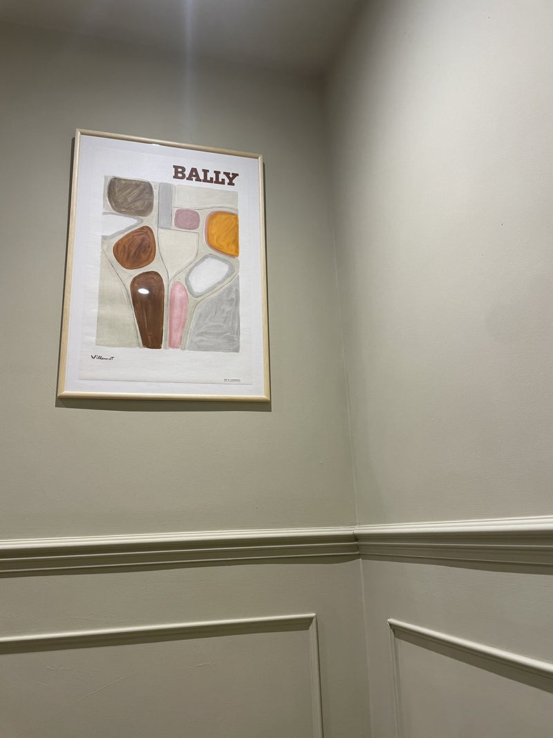 An original Bally poster framed in a panelled hallway
