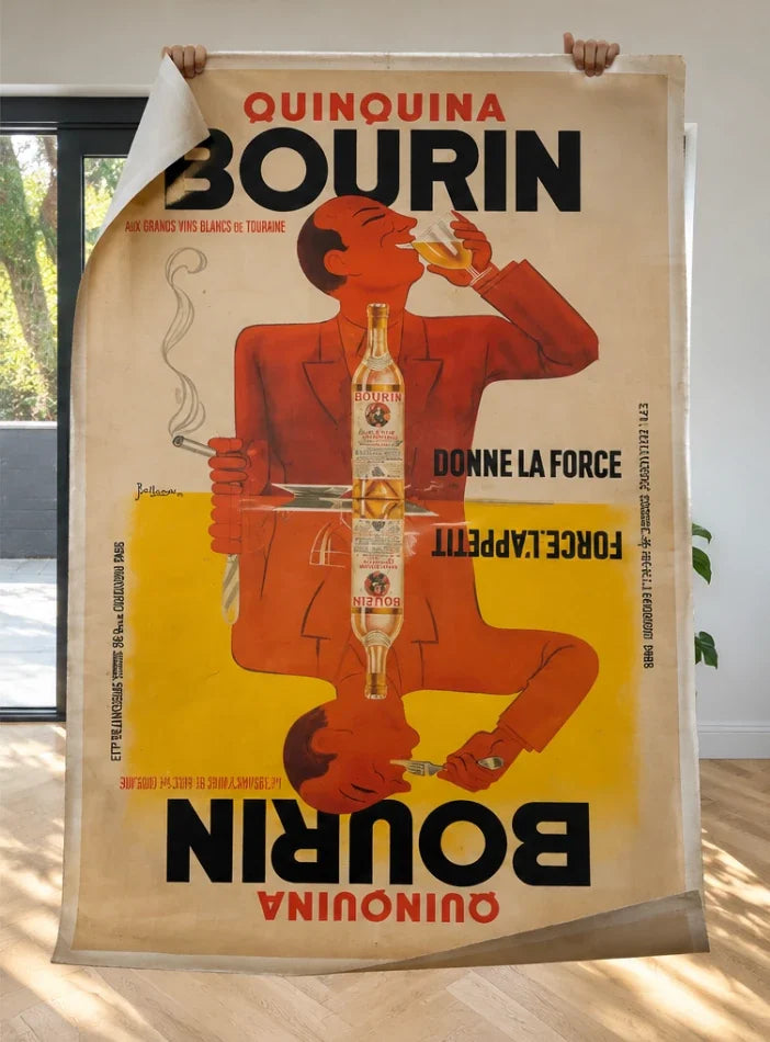 An unframed original Quinquina Bourin poster held open by hand