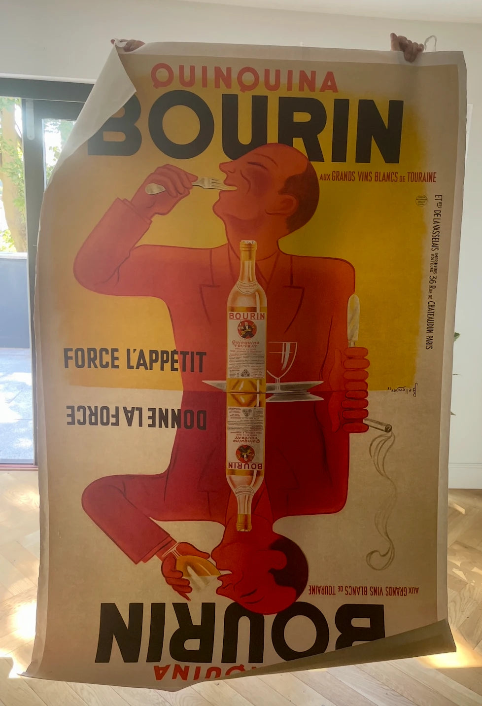 A large original Quinquina Bourin poster by Leonetto Cappiello held open by hand before packing